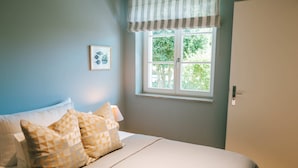 Une chambre à coucher avec un lit, des oreillers, une fenêtre et une porte.