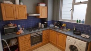 A compact kitchen with wooden cabinets, a microwave, stove, sink, and a washing machine. - Single Occupancy - Lovely Area - 5min to dlr (London)