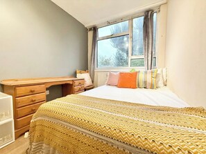 A bedroom with a bed, a wooden desk, and a window. - Single Occupancy - Lovely Area - 5min to dlr (London)