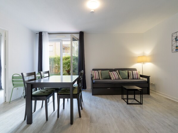 A modern living room with a dining table, chairs, a sofa, and a lamp. - Bright apartment for 4 people, with a garden (Grasse)