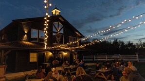 A wooden building with string lights, outdoor seating, and a white fence. - Fjelleventyret (Skjaak)