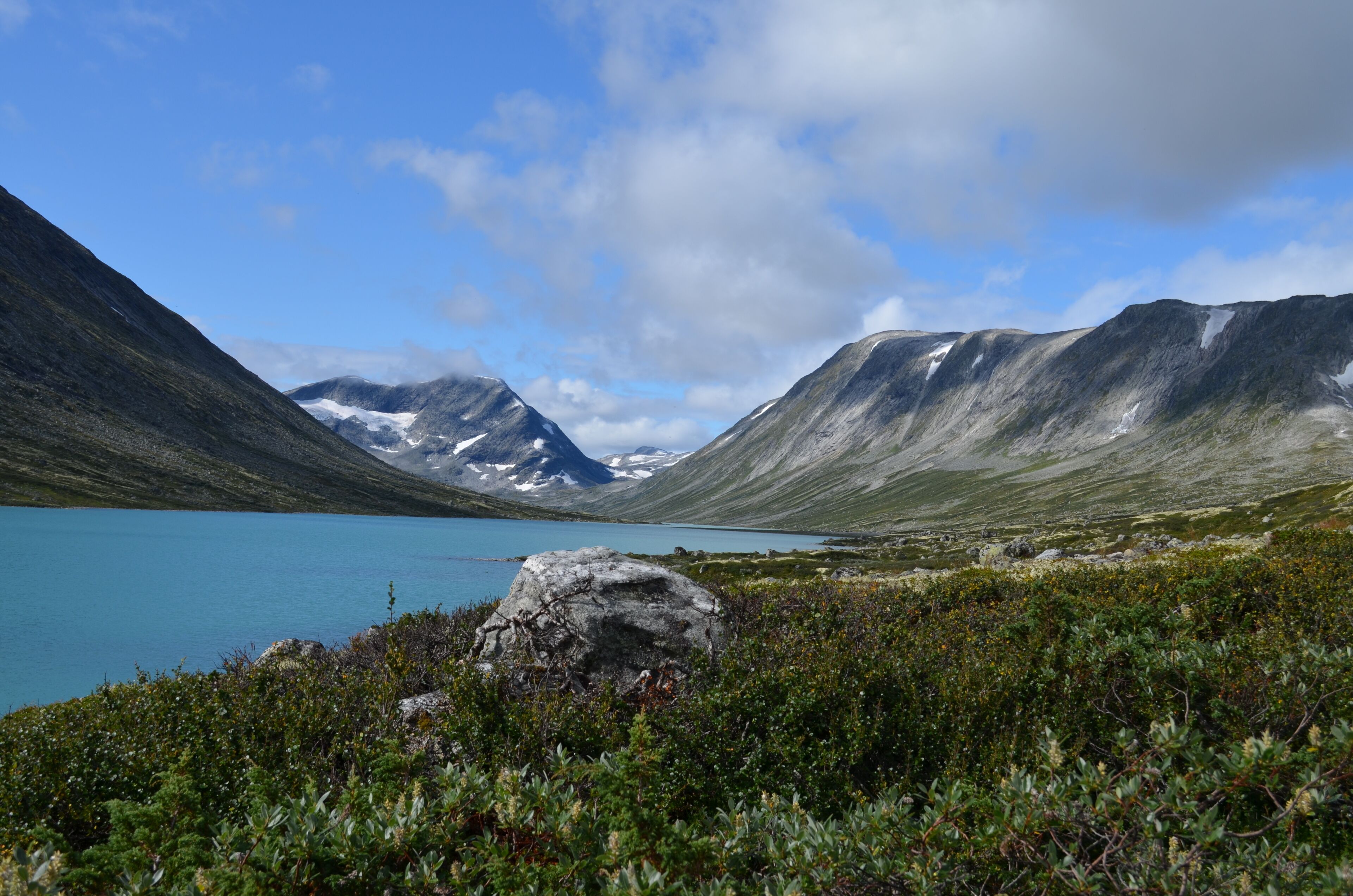 Eine Berglandschaft mit einem See, felsigem Gelände und vereinzelter Vegetation.