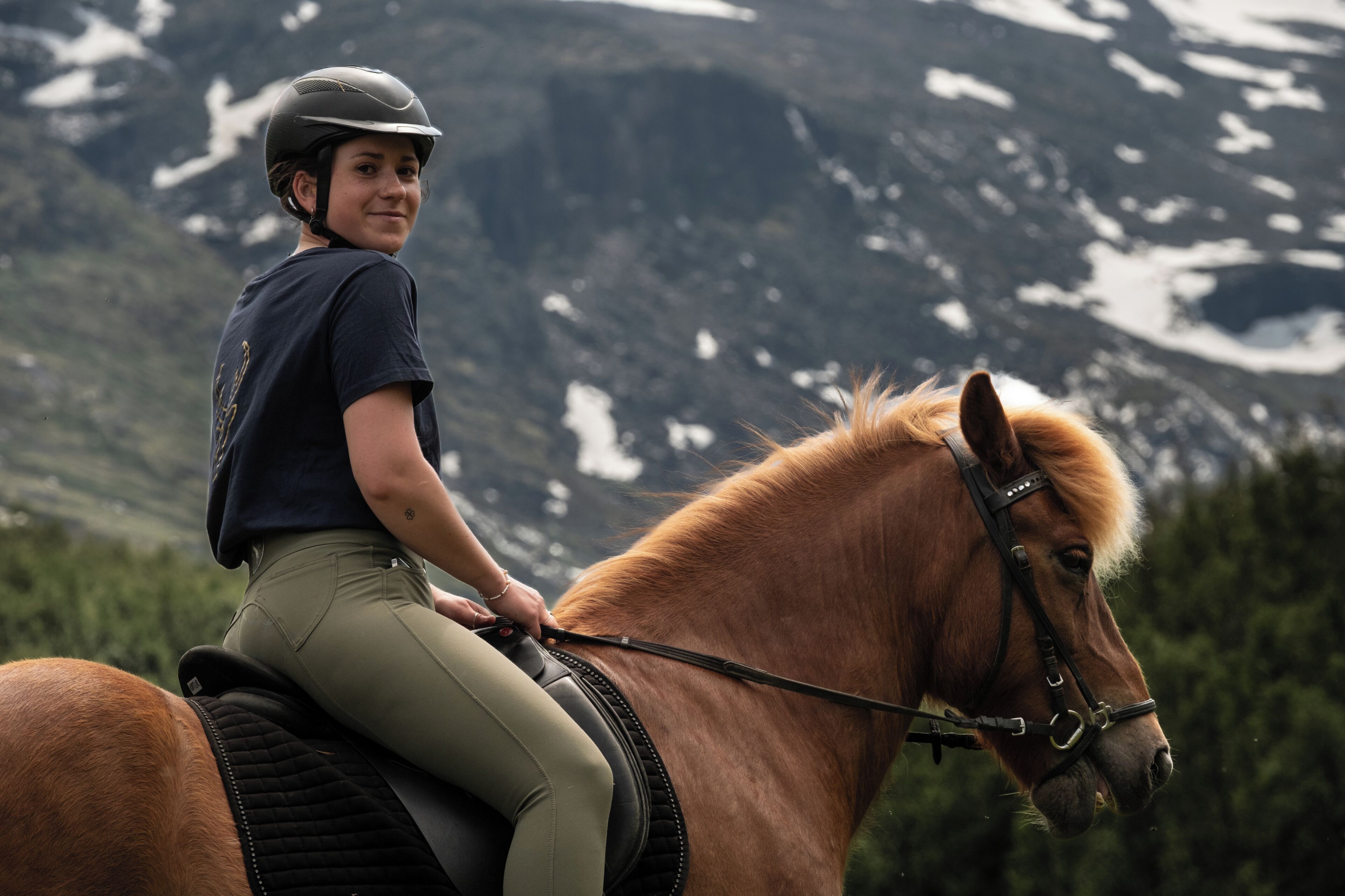 Una persona cavalca un cavallo sullo sfondo di montagne.