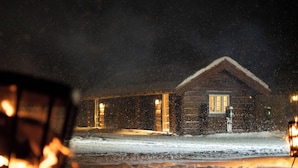 A wooden cabin with a snow-covered ground, a visible door, and a window. - Fjelleventyret (Skjaak)