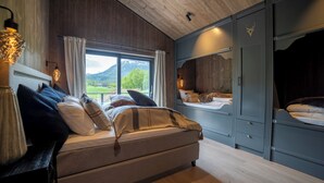 A bedroom with a bed, a window with a view of a mountain, and a wardrobe. - Fjelleventyret (Skjaak)