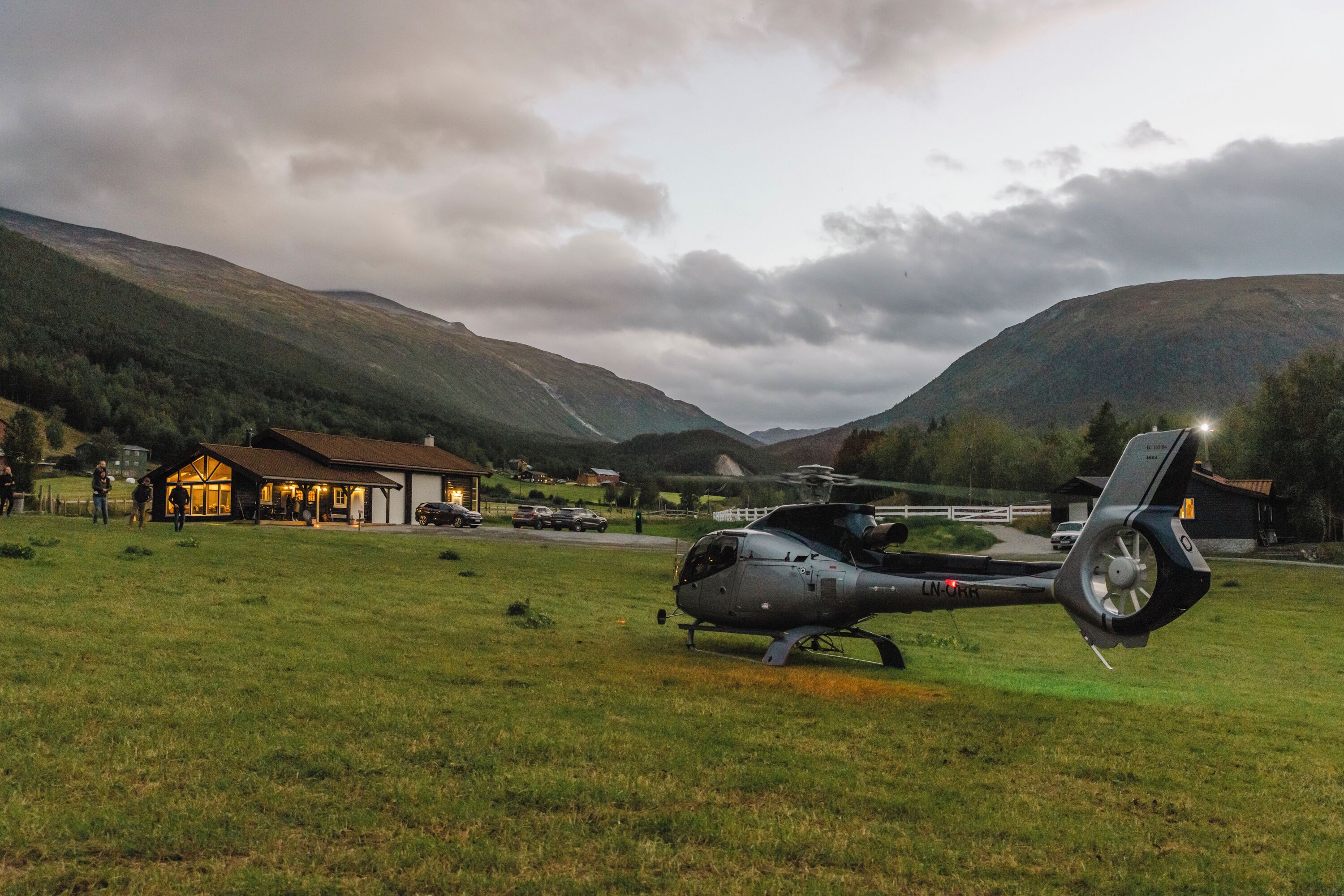 A helicopter parked on a grassy field with a building in the background.