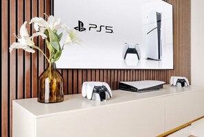 A modern room with a white console table, a PS5, and a vase of white flowers. - Mayfair Confidential (Greater London)