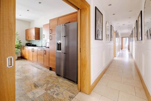 A modern kitchen with wooden cabinets, a stainless steel refrigerator, and a tiled floor. - LUX 4BR 3BA in the ♥️ of Mayfair on Park Lane ❄️ Air Conditioning | Sleeps 12 (Greater London)