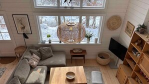 Una sala moderna con un sofá modular, una mesa de centro de madera, un sillón gris, un televisor y una estantería.