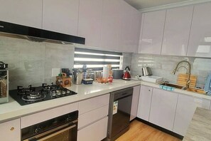 A modern kitchen with a gas stove, dishwasher, and a window with blinds.