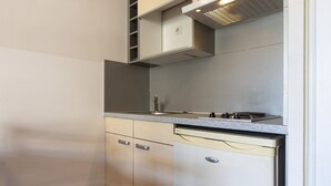 A compact kitchen with a built-in stove, a dishwasher, and a cabinet above the counter.