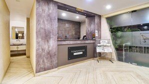 A reception area with a marble counter, a sign reading 'TOWNHOUSE & Company-Serviced,' and a glass wall with a plant.