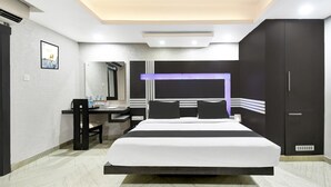 A modern hotel room with a large bed, a desk, and a wardrobe.