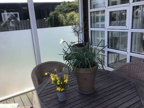 A balcony with a table, chairs, a potted plant, and a wicker basket. - 4 Star Holiday Home in Karrebaeksminde (Karrebæksminde)