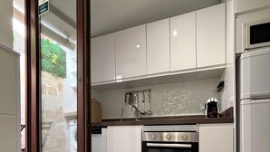 Una cocina moderna con alacenas blancas, horno empotrado y refrigerador.