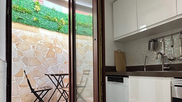 Una cocina moderna con lavavajillas, armarios blancos y una pared de piedra.