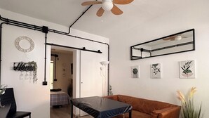 Una sala de estar moderna con un sofá de cuero marrón, una mesa negra y un ventilador de techo.