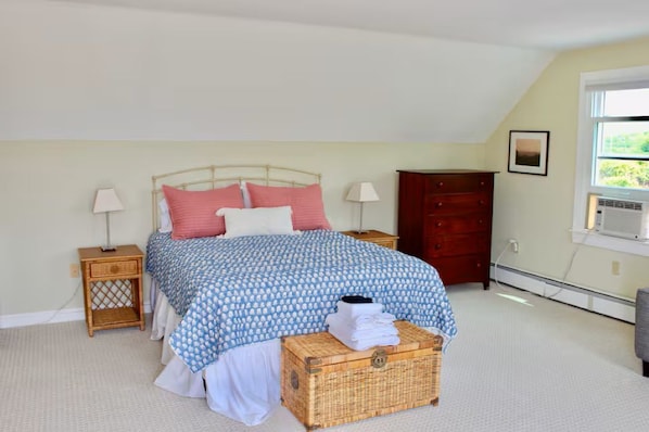 A bedroom with a bed, nightstands, a dresser, a window, and a wall-mounted air conditioner. - Honeysuckle Suite with AC & Deck (New Shoreham)