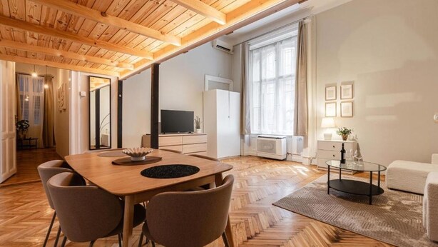 Ett modernt vardagsrum med ett träpanelat tak, en matplats med ett träbord och stolar, en soffa och en tv.