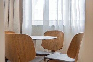 A dining area with a round table and three wooden chairs. - Cascais Loft by Olala Homes (Cascais)