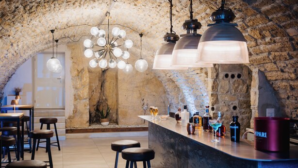 A bar area with stools, a bar counter, and hanging light fixtures. - Les Vieux toits (Hauterive)