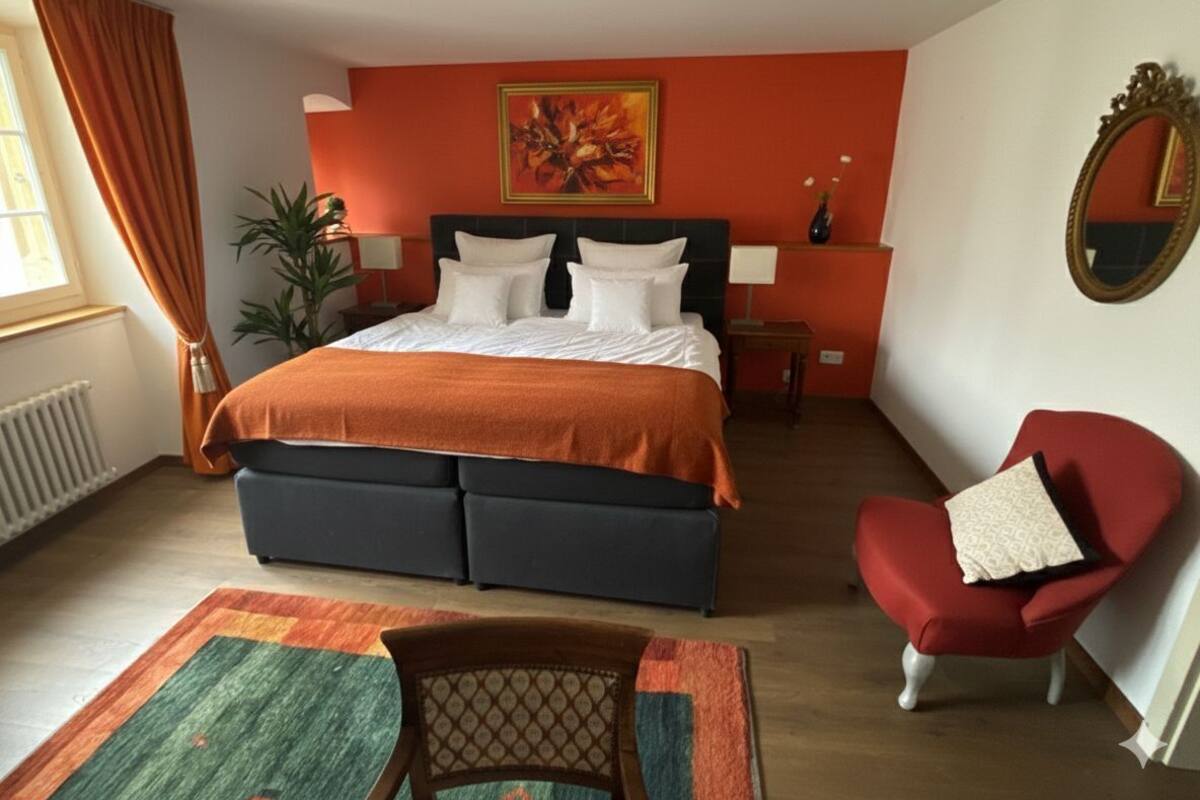 Un dormitorio con cama, una silla, un espejo y un cuadro en la pared.