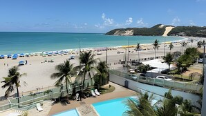 Un resort en la playa con piscina, sombrillas y vistas al océano.