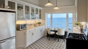 A kitchen with white cabinets, a microwave, a stove, and a view of the sea. - The Jenswold House on Lake Superior with Panoramic Views and Lake Access (Duluth)