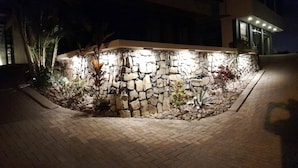 A stone wall with plants and a paved area. - Oceanview Modern Guest House With Pool (Sardinal)