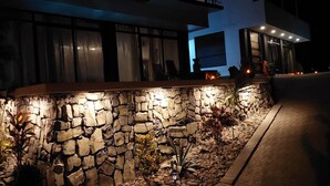 A modern building with a stone facade and a well-lit entrance. - Oceanview Modern Guest House With Pool (Sardinal)