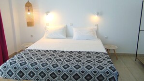 A bed with a patterned bedspread, two white pillows, and two wall-mounted lights. - 106 First Floor (Faliraki)