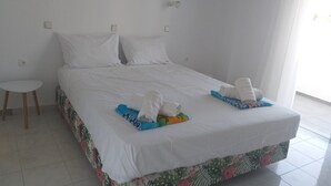 A hotel room with a large bed, a small table, and a hanging light fixture. - 14 Ground Floor (Faliraki)