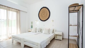 Quarto com cama grande, mesas de cabeceira, guarda-roupa e uma obra de arte na parede.