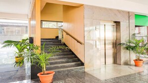 A modern interior with a staircase, elevator, and potted plants. - Deluxe With Twin Bed The Pallagio (Visakhapatnam)