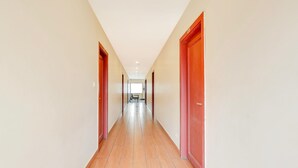 A long, narrow hallway with wooden floors and red doors on both sides. - Deluxe With Twin Bed The Pallagio (Visakhapatnam)