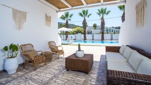 A sunlit patio with wicker furniture, a white sofa, and a potted plant. - 11 Ground Floor (Faliraki)