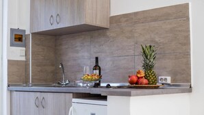 A kitchen with wooden cabinets, a built-in oven, and a fruit basket on the counter. - 107 First Floor (Faliraki)