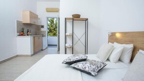 A modern hotel room with a bed, pillows, a bedside table, a wardrobe, and a view of the outdoors. - 107 First Floor (Faliraki)