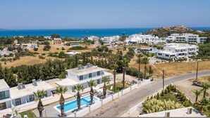 A modern resort with a swimming pool, palm trees, and a view of the sea. - 105 First Floor (Faliraki)