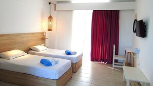 A hotel room with two beds, a desk, a television, and a window with red curtains. - 105 First Floor (Faliraki)
