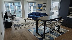 Un salon moderne comprenant un canapé, une table à manger avec des chaises, une table basse et un téléviseur.