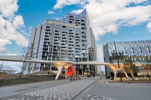 Ein modernes Gebäude mit Glasfassade, Fußgängerweg und einer markanten roten Struktur.