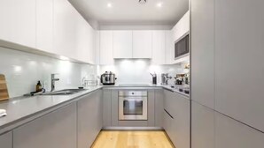 Eine moderne Küche mit grauen Schränken, Edelstahlgeräten und Holzboden.