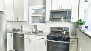 Una cucina moderna con mobili bianchi, elettrodomestici in acciaio inossidabile, una finestra e una pianta in vaso.