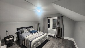 Una camera da letto con un letto, un comodino e una finestra con tende.