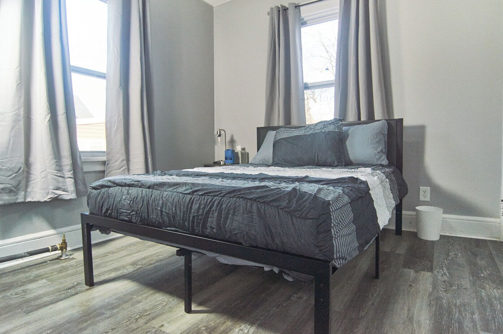 A bedroom with a bed, curtains, a nightstand, and a window.