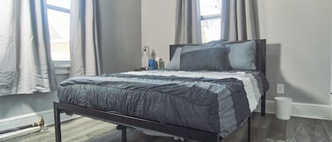 A bedroom with a bed, curtains, a nightstand, and a window.