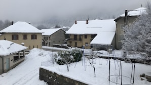 A snow-covered residential area with houses, a stone wall, and a swing set.