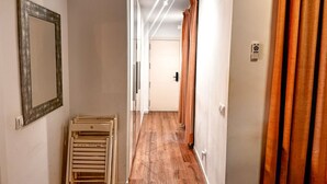 Ein Flur mit Holzboden, einem Spiegel links und Vorhängen rechts.