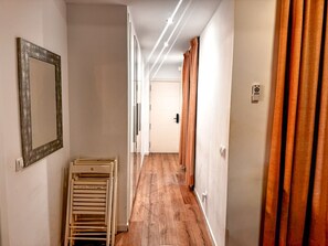 Ein Flur mit Holzboden, einem Spiegel links und Vorhängen rechts.